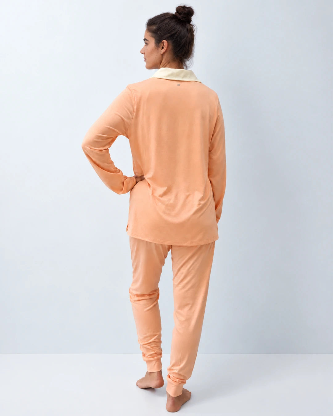Vista trasera del pijama con top integrado cuello sastre y pantalón puño color melocotón
