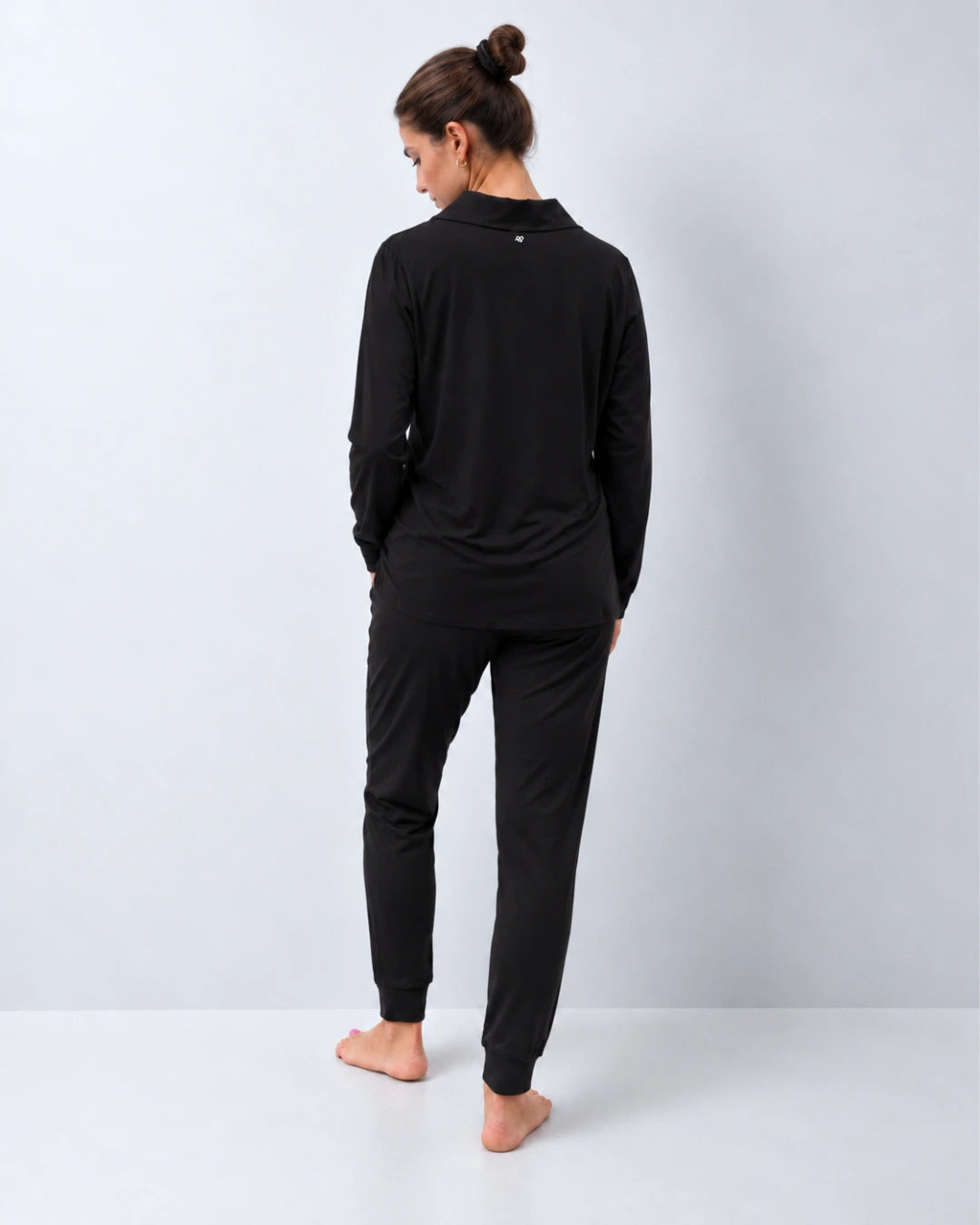 Vista trasera del pijama con top integrado cuello sastre y pantalón puño color negro
